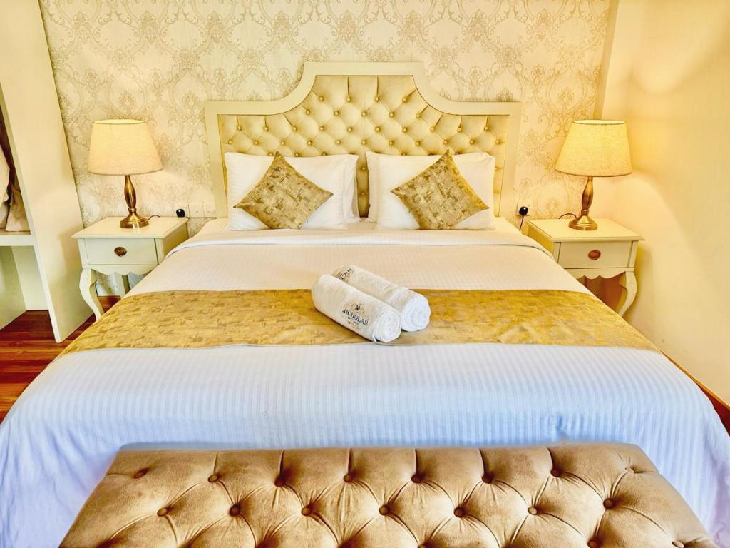 a bedroom with a large white bed with two towels on it at Nicholas Cottage in Nuwara Eliya