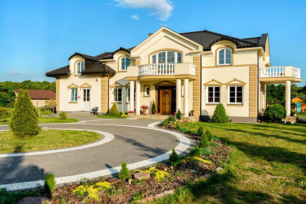 una gran casa amarilla con un camino sinuoso en Pensjonat nad Strugą, en Stryków