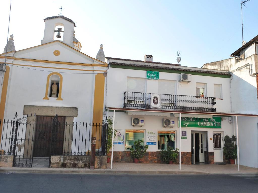 a white building with a bell tower on a street at Hostal Via Del Caminante in Madrigalejo