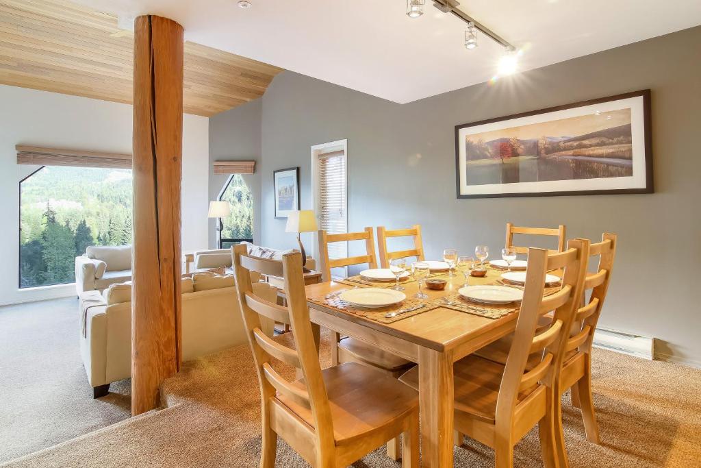 uma sala de jantar e sala de estar com uma mesa de madeira e cadeiras em Snowbird by Elevate Vacations em Whistler