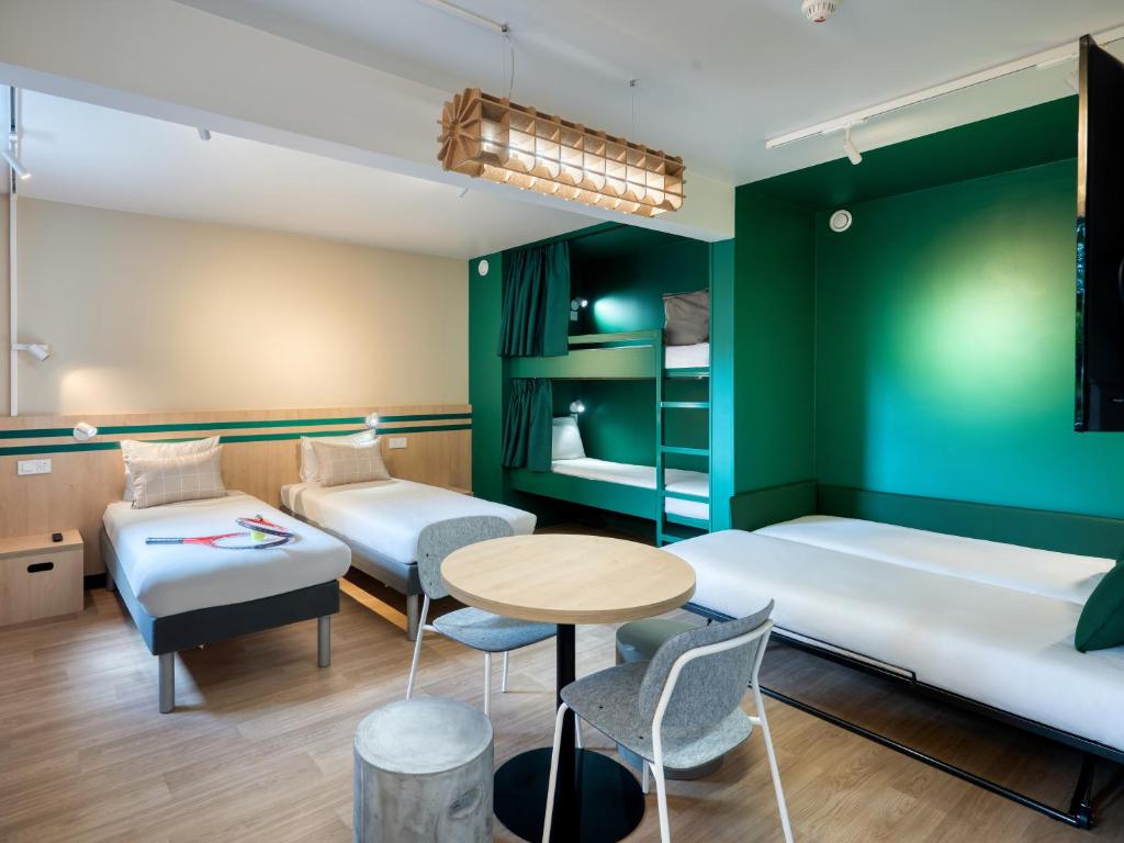 a room with two beds and a table and chairs at Ibis Budget Orly Chevilly Tram 7 in Chevilly-Larue