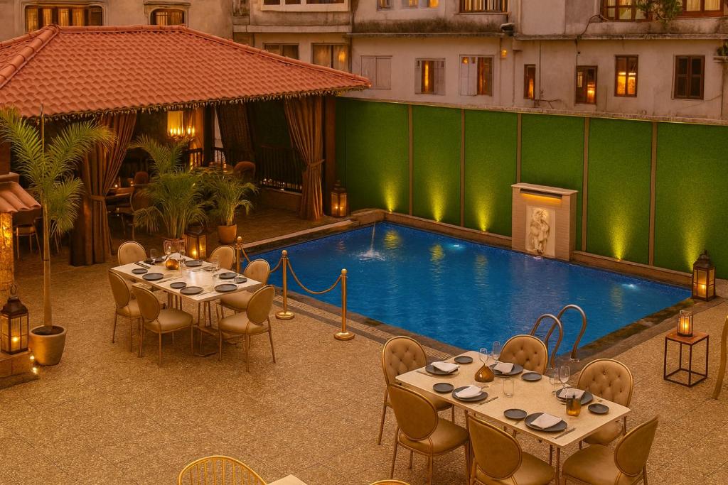 ウダイプールにあるHotel Grand Bhagwat with rooftop swimming poolのテーブルと椅子付きのスイミングプールを併設しています。