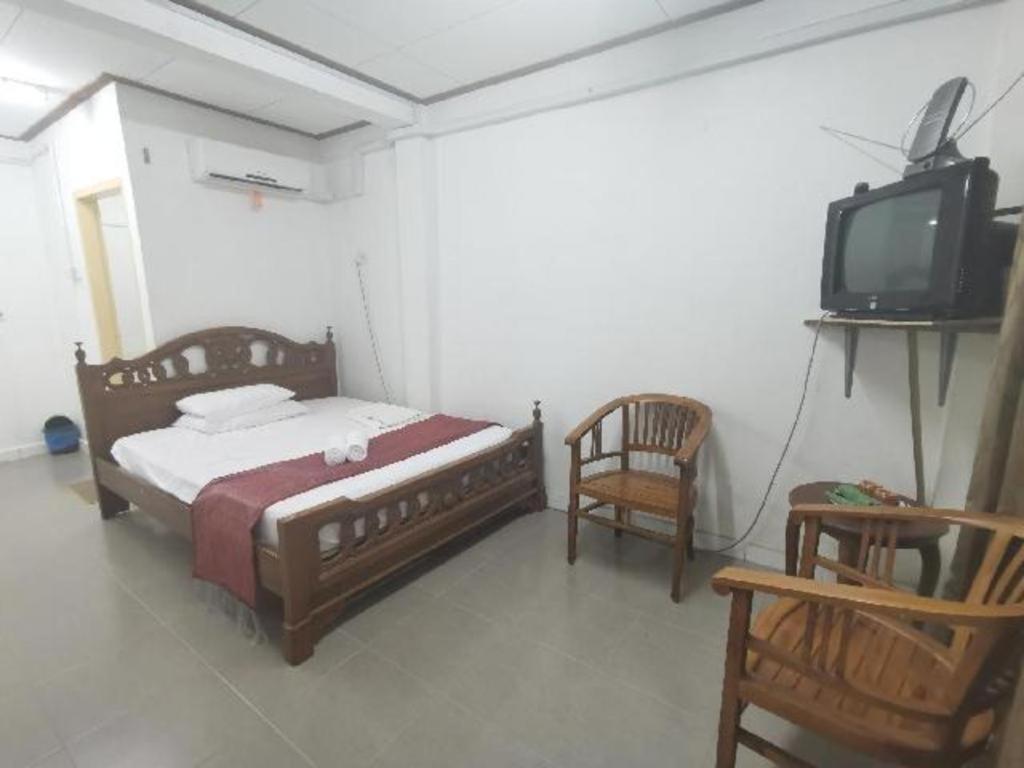 a bedroom with a bed and a tv and a chair at Nipah River view in Kampong Losong