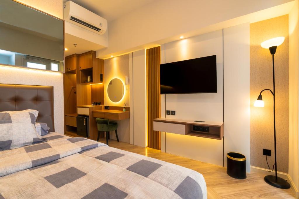 a bedroom with a bed and a flat screen tv at Tokyo Riverside Apartemen PIK 2- Kaito Inn Royale in Muara