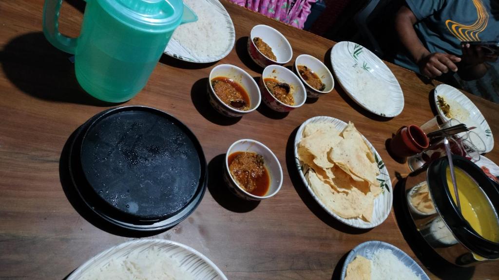 a wooden table topped with plates and bowls of food at View Porjoton Mairung Gaon Homestay in Rishop