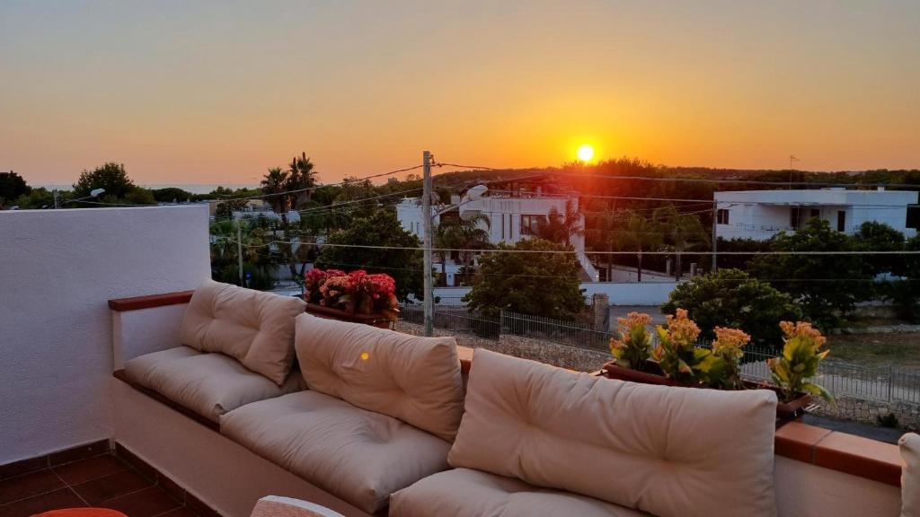 un sofá en un balcón con puesta de sol en el fondo en Vacanze in Villa, en Nardò