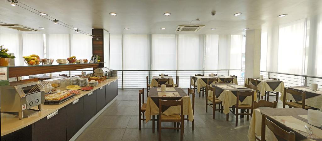 a restaurant with tables and chairs and a buffet at Hotel Panorama in Lido di Jesolo