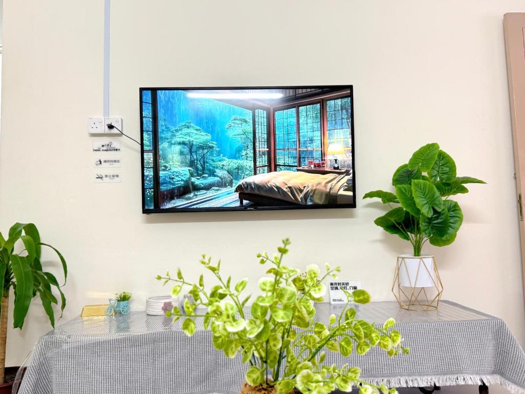 a television hanging on a wall with two tables at 10pax Near Ipoh Town Family Home in Ipoh