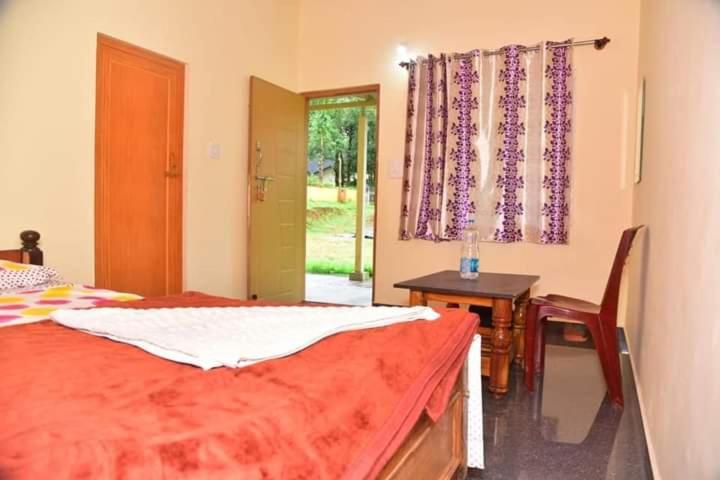 a bedroom with a bed and a desk and a window at Ganav home stay in Chikmagalūr