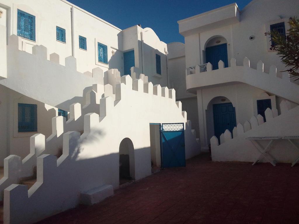 a white building with stairs and a blue door at Taguermess 1 in Djerba
