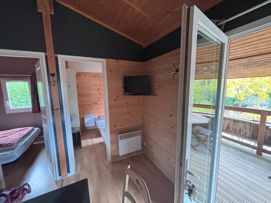 a room with a wooden wall with a television and a balcony at chalet montana 5_4 pers in Roquefeuil