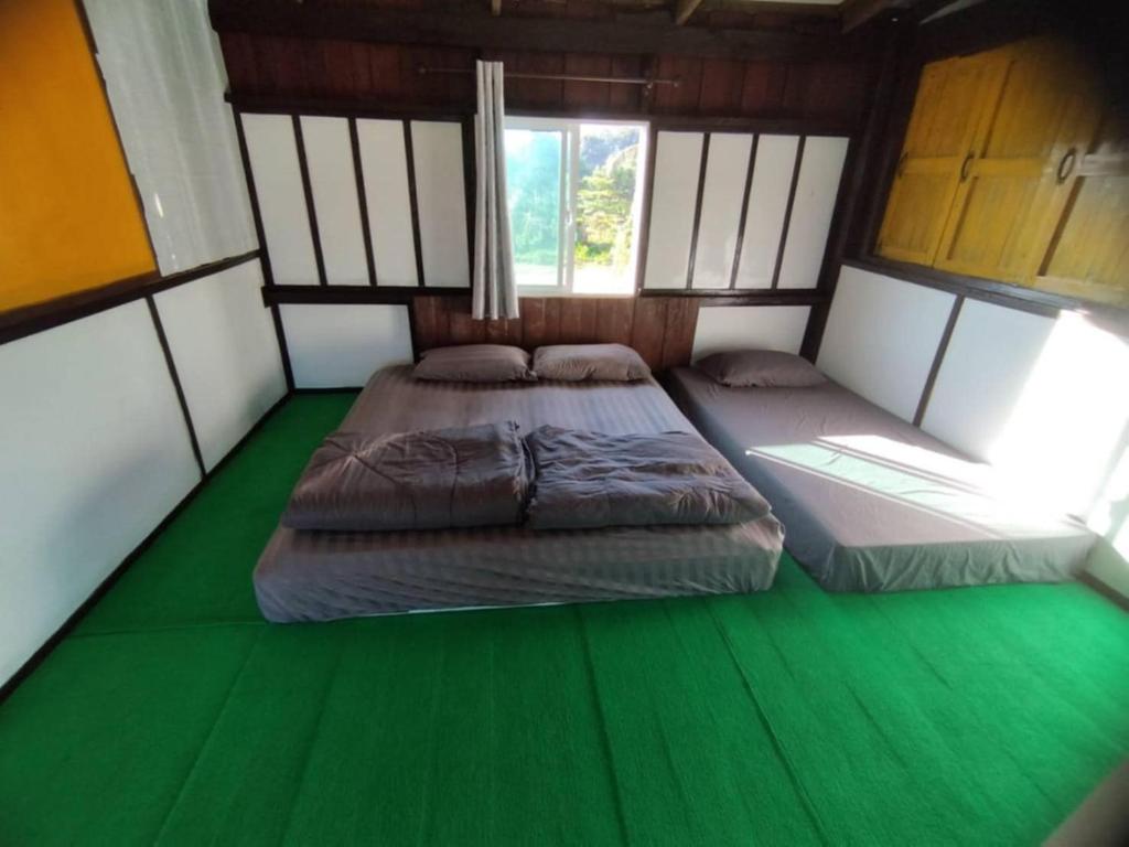 two beds in a room with a green floor at มองนาภูคาน่านโฮมสเตย์ in Ban Thon (1)