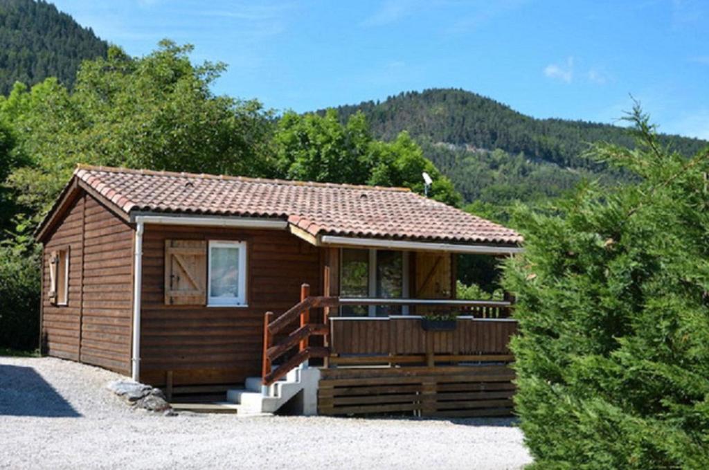 a small cabin with a porch and mountains in the background at Chalet Montana 4 pers in Roquefeuil