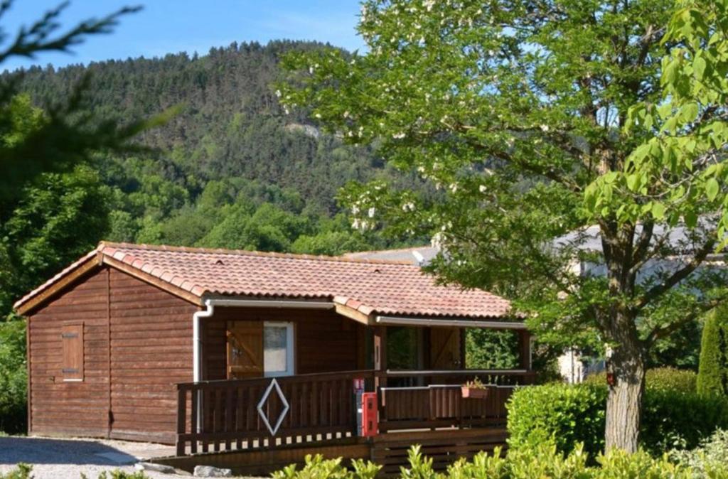 a small cabin with a tree and mountains in the background at Chalet Montana pmr 4 pers in Roquefeuil