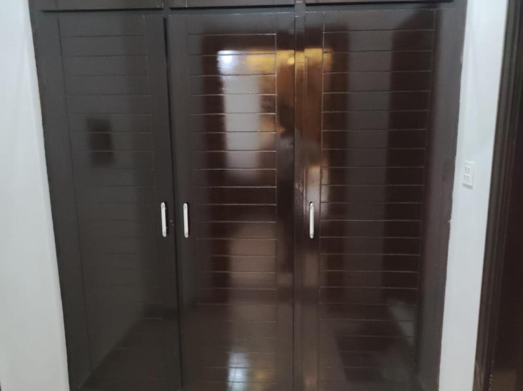 a glass cabinet with a door in a room at Osma Living Apartment Peshawar in Peshawar