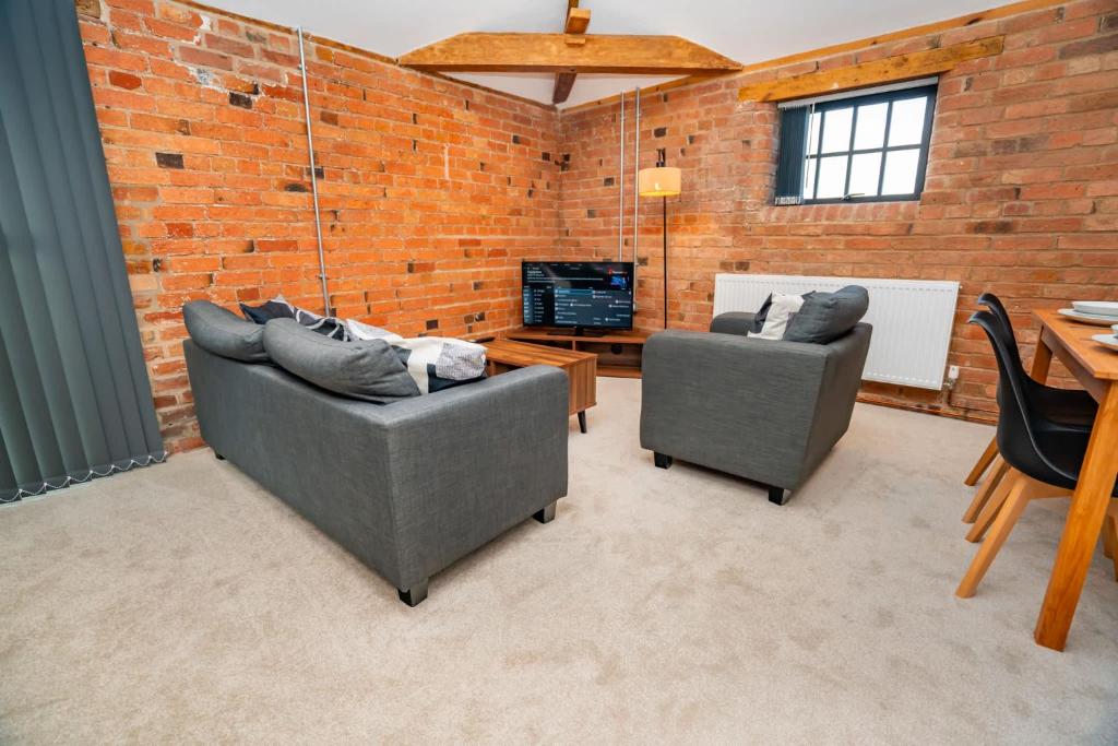 a living room with two couches and a brick wall at Spacious 2 Bedroom Apartment in Central Newark in Newark upon Trent