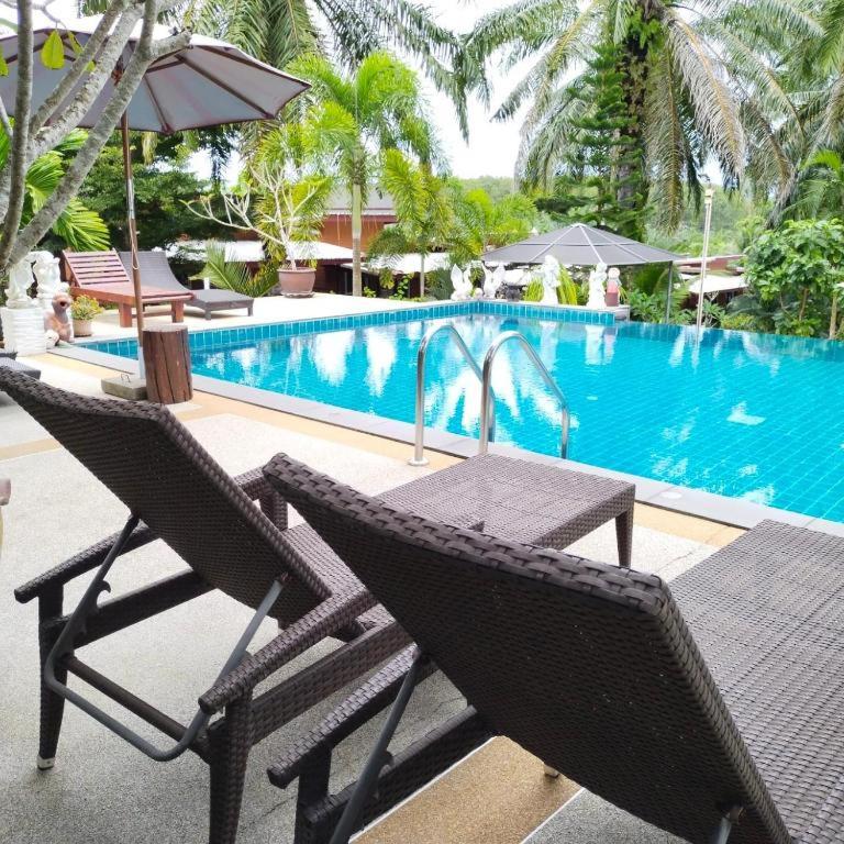 a table and chairs next to a swimming pool at Palmthien Pool Villa Aonang in Ao Nang Beach