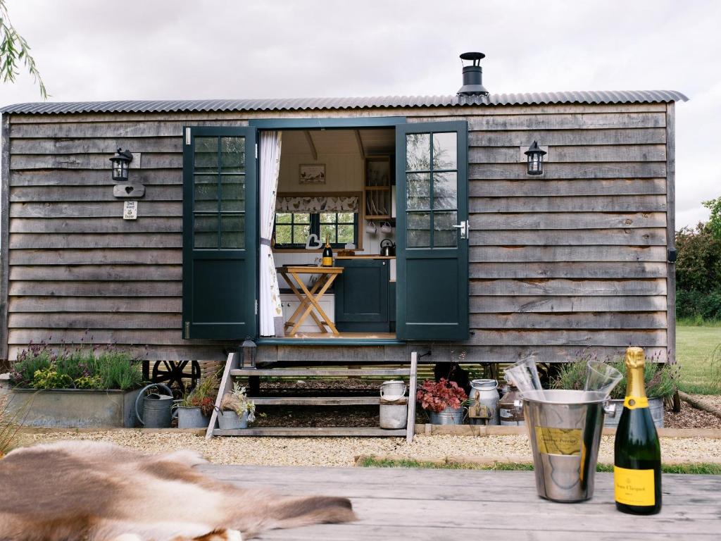 a dog laying on a table in front of a tiny house at Poppie's Shepherds Hut at Shepherds Lodge Retreat and Wellness in Nottingham