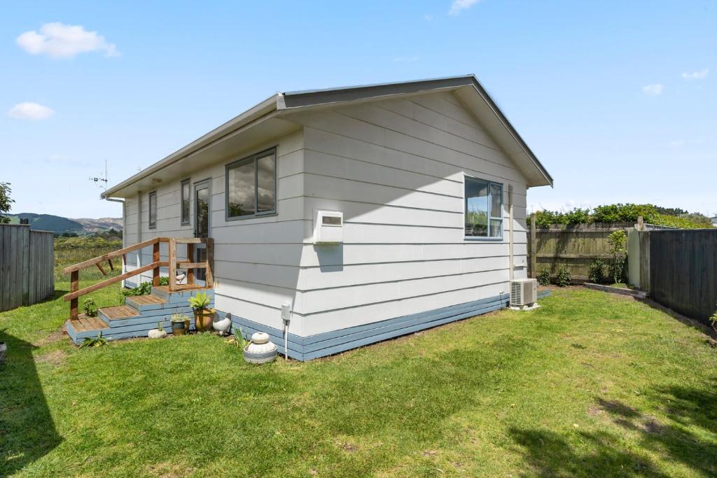 a small white house in a yard at Restful on Rutherford - Waikanae Holiday Home in Waikanae