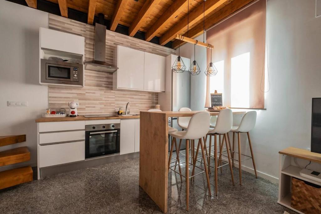 a kitchen with white cabinets and bar stools at Apartamento en casco histórico Exclusivo con AC in San Martín de Valdeiglesias