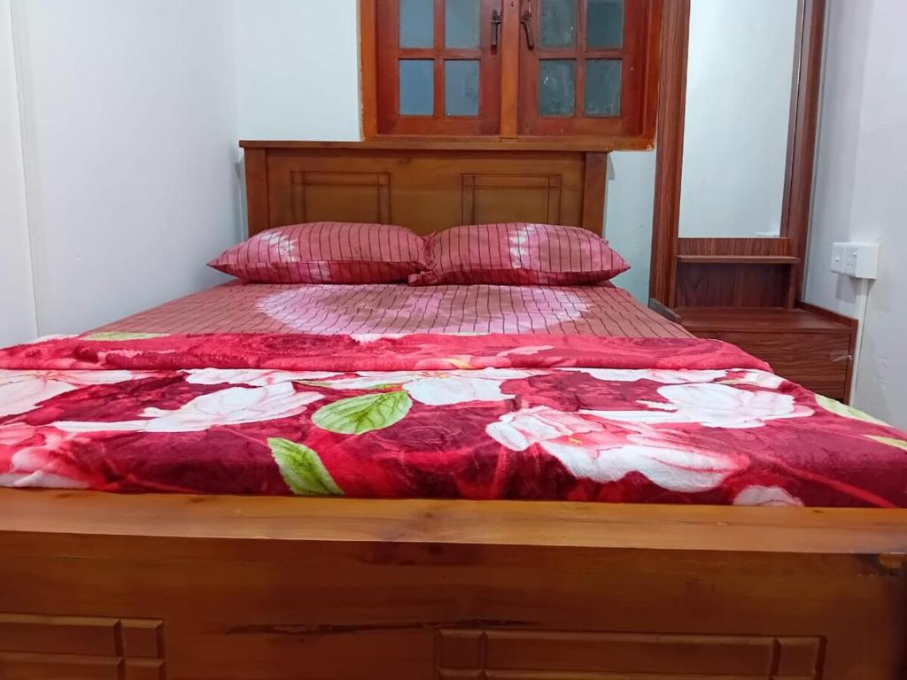 a bed with a red and white comforter and pillows at Blessed guest Nuwara eliya in Nikawatawana