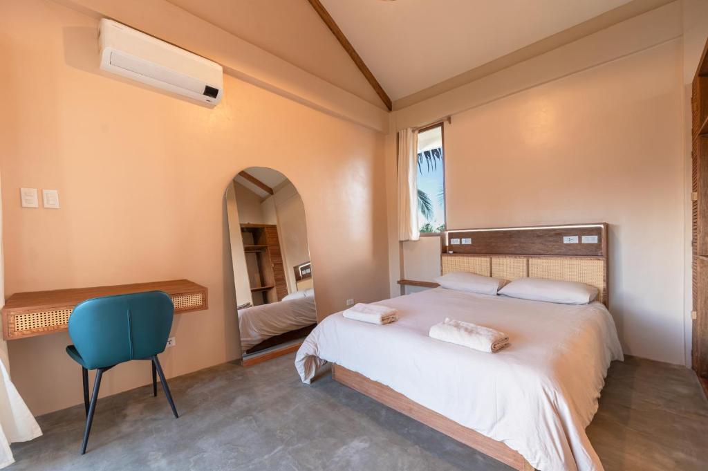 ein Schlafzimmer mit einem Bett und einem blauen Stuhl in der Unterkunft Villa Armonia Siargao in General Luna