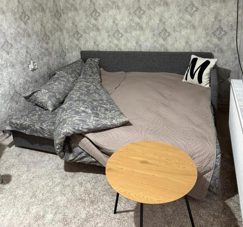 a bedroom with a bed and a wooden table at Домик в общем дворе с хозяином in Komrat