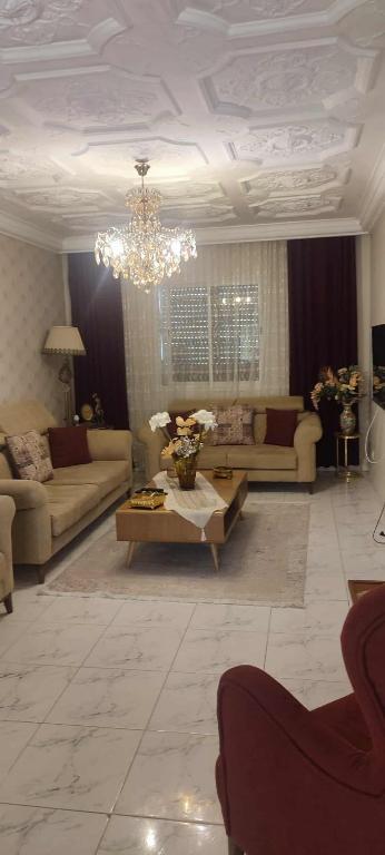 een woonkamer met banken en een kroonluchter bij La maison du bonheur in Ariana
