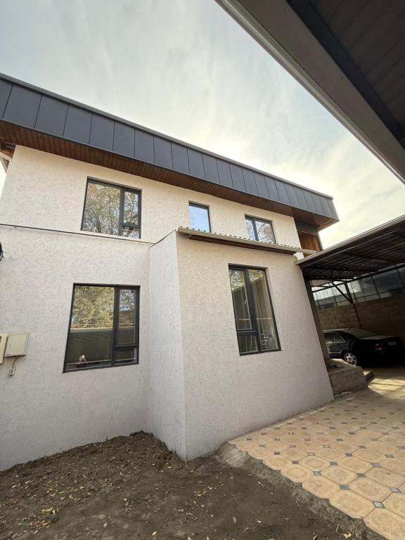 een wit huis met een zwart dak bij TaTa Guest House in Bisjkek