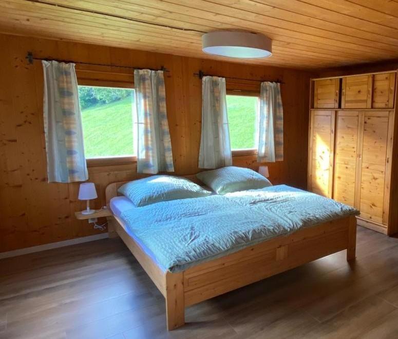 a bedroom with a bed with blue sheets and windows at Haus Renard in Rodund