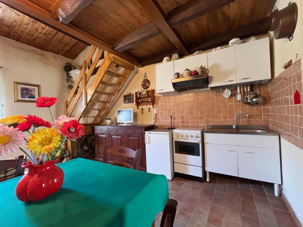 a kitchen with a table with a vase of flowers on it at il nido di latera in Latera