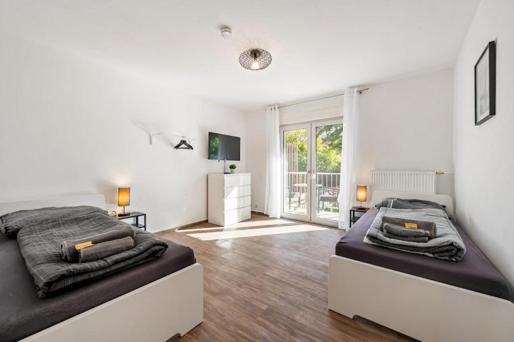 a bedroom with two beds and a large window at BIR02 Wohnung mit Garten in Rüsselsheim! in Rüsselsheim