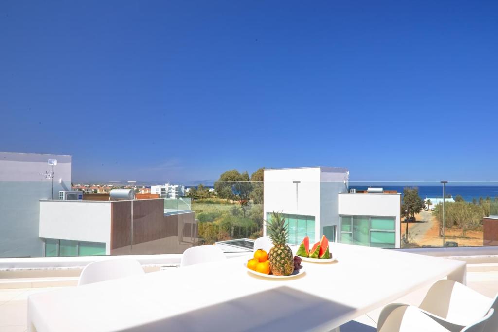 a bowl of fruit on a white table on a balcony at Seaview Luxury Villa Jacuzzi & Pool! 2 Min Beach in Protaras