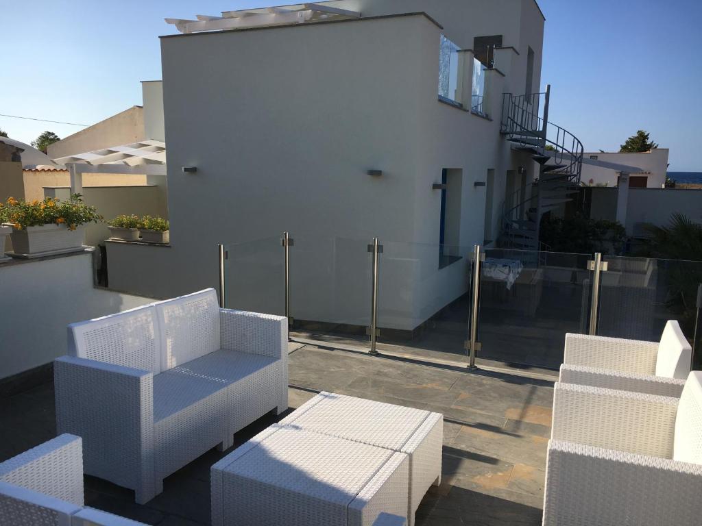 a balcony with white furniture and a white building at Le case di Palma in San Vito lo Capo