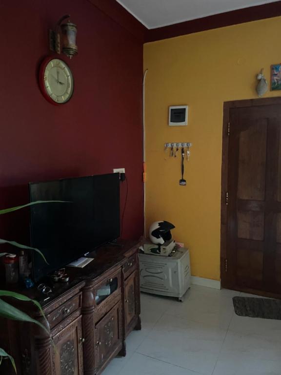 a living room with a tv and a clock on the wall at Sebastian Homes in Madikeri