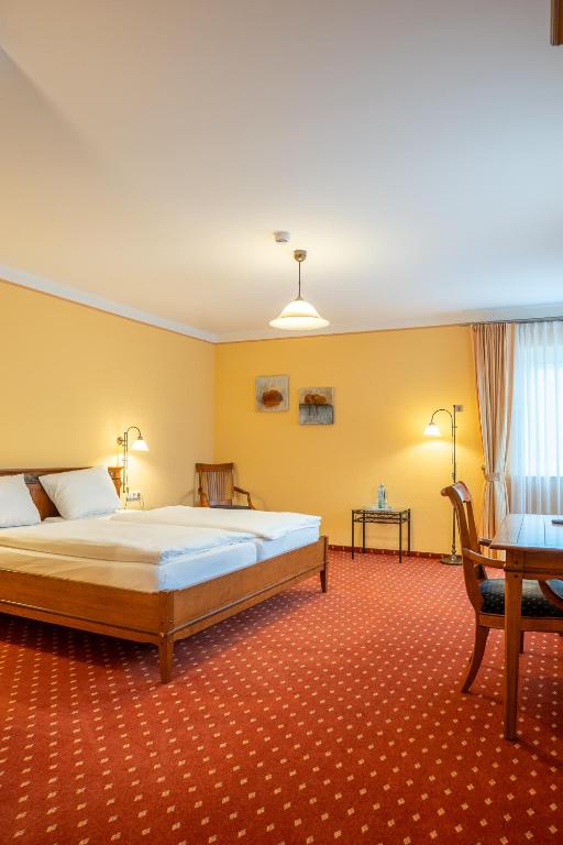 a bedroom with a large bed and a desk at Hotel Kaisergarten Neuenrade in Neuenrade