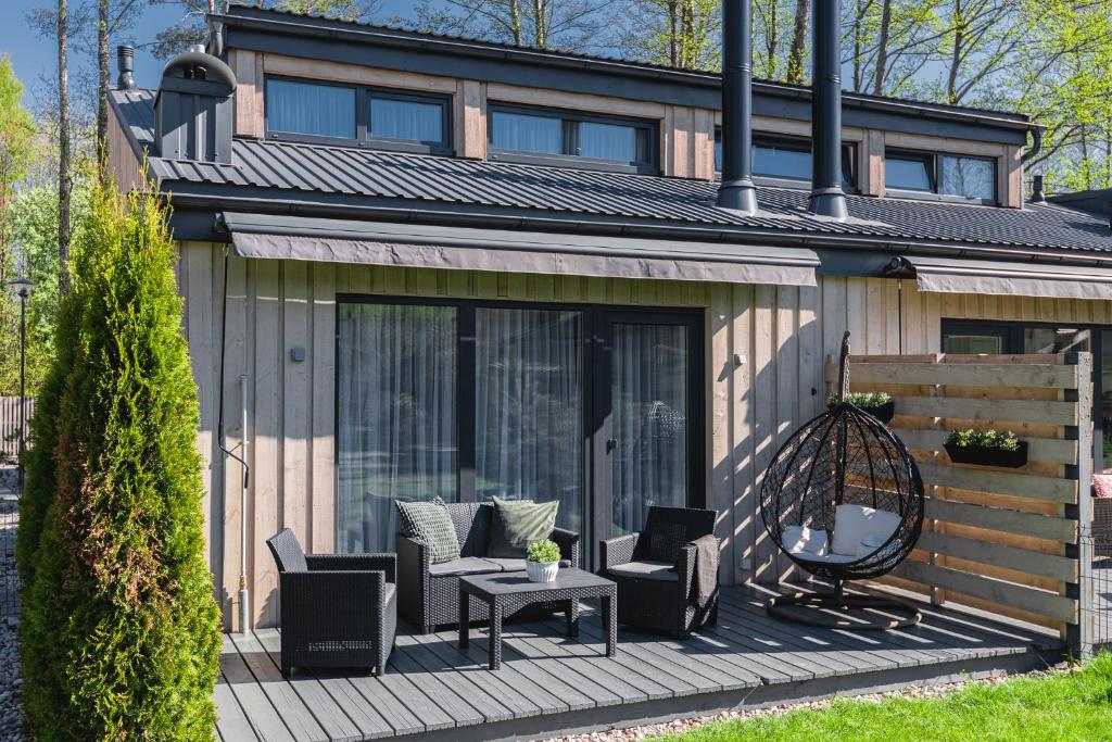 une maison dotée d'une terrasse avec des chaises et une table dans l'établissement Žalia kopa near the beach apartments, à Palanga