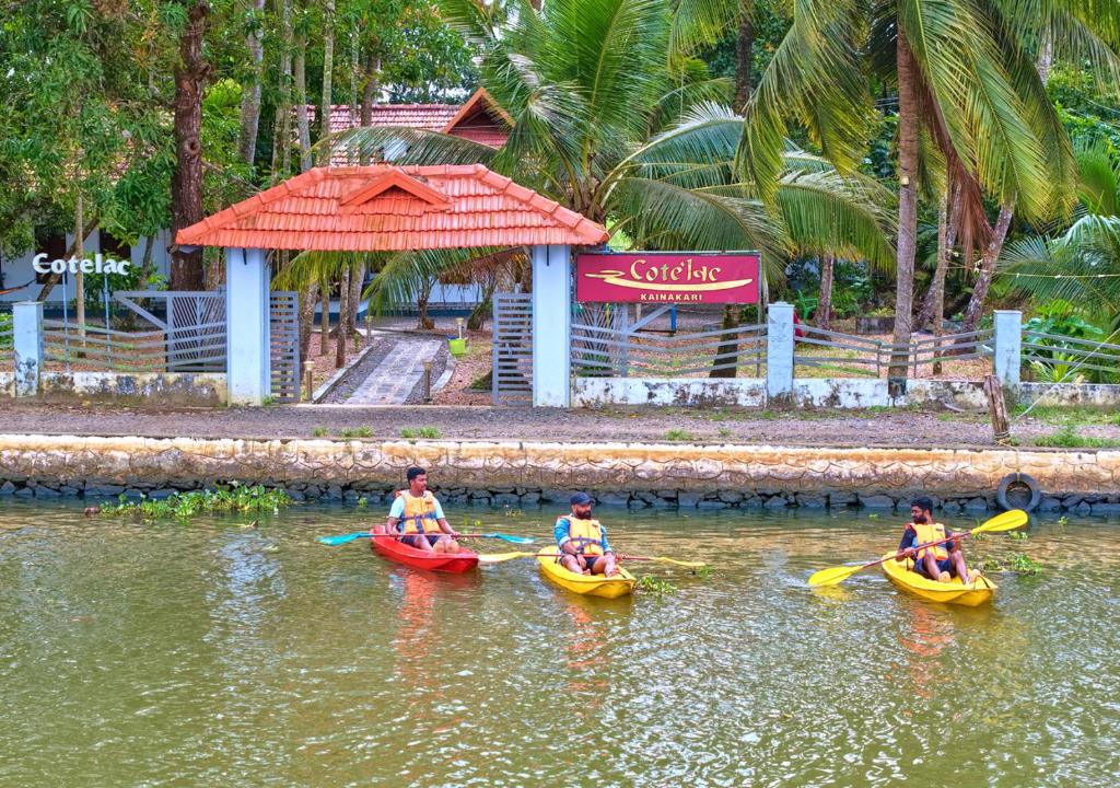 3 personnes sont dans des kayaks dans l'eau dans l'établissement Cotelac Heritage Lake Resort Alleppey by VOYE HOMES, à Alappuzha