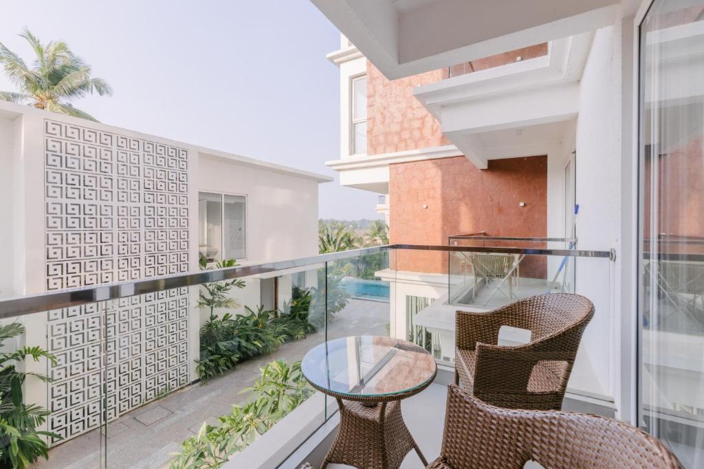 ein Balkon mit Stühlen und einem Glastisch in der Unterkunft Humble Pineapple by Da Alohas in Calangute
