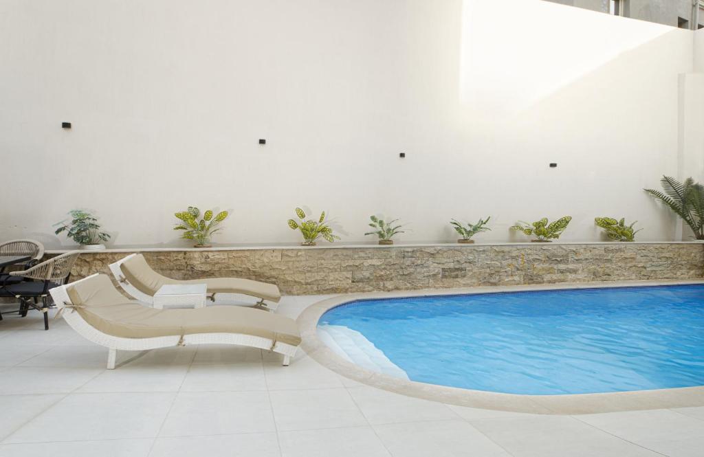 a swimming pool with two chairs and a table at Rivana Residence New Cairo - Pool & GYM Access in Cairo