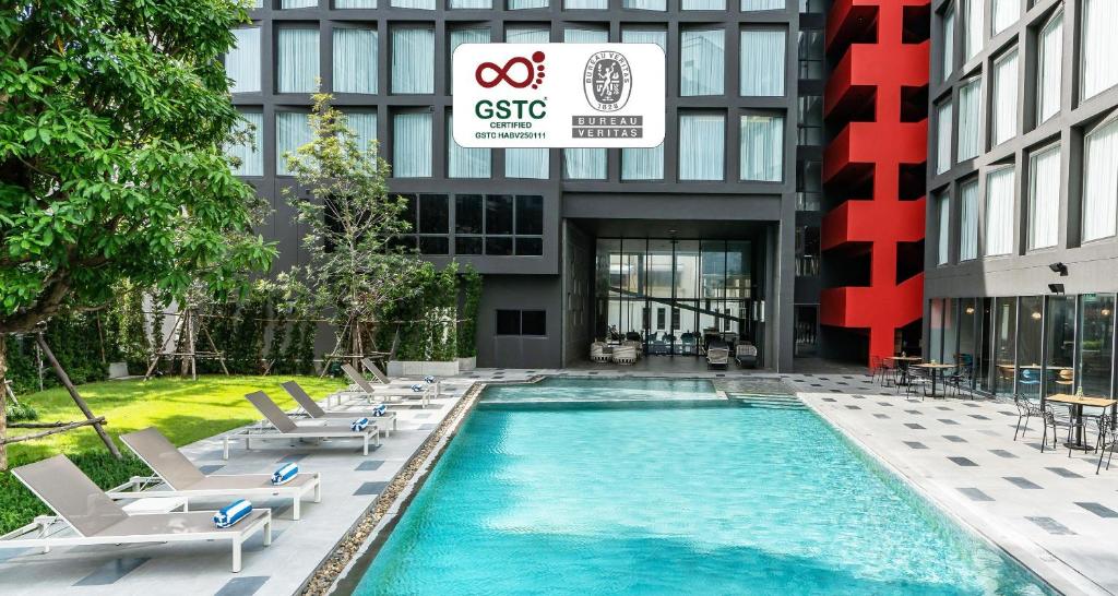 a swimming pool with lounge chairs and a building at Best Western Plus Nexen Pattaya in Pattaya Central