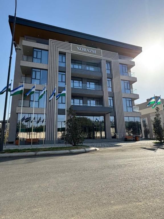 a hotel with flags in front of a building at Khorazm Hotel in New Uzbekistan Park in Teshabayguzar