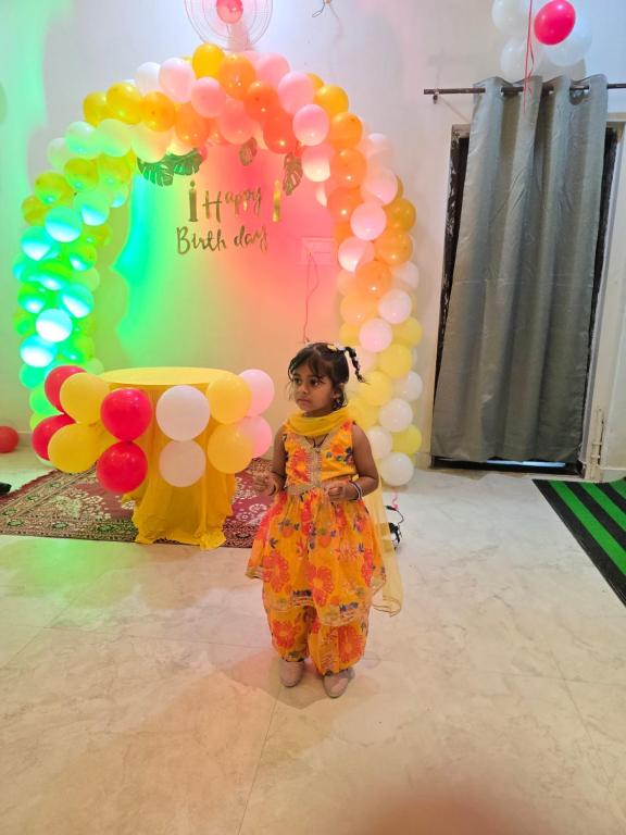 a little girl standing in front of a bunch of balloons at Hotel Shri Ram Gopal Seva Dham in Vrindāvan