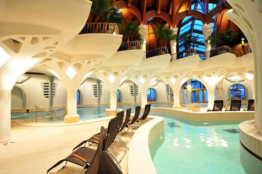 une grande piscine intérieure avec des chaises dans un bâtiment dans l'établissement Csilla Apartman, à Makó
