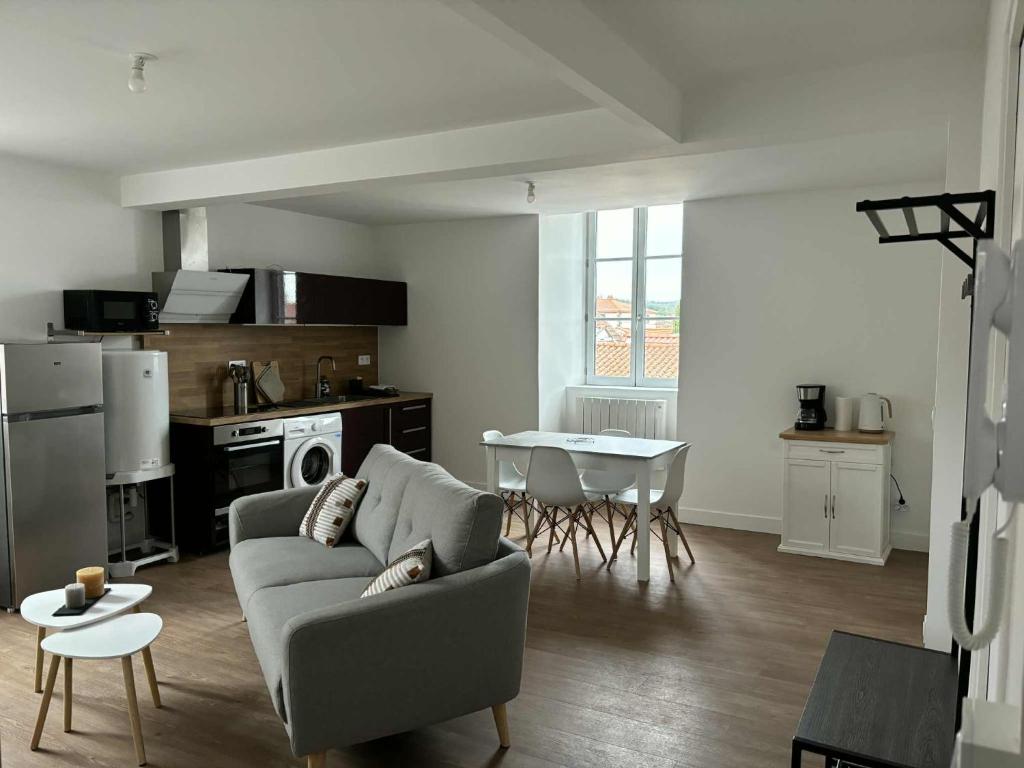 Una sala de estar con un sofá y una mesa y una cocina. en Appartement, en Combronde
