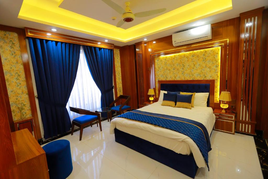 a hotel room with a bed and a desk and chair at Qinwan Hotel & Suites in Rawalpindi