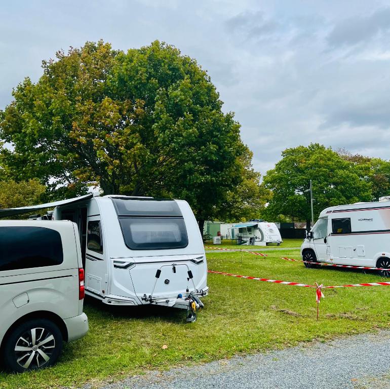 Dos furgonetas blancas estacionadas en un campo con árboles en 5 Sterne Wohnwagen - incl parking - reserv Stellplatz - direkt Messegelände-Duschräume- CARAVAN at Fair Ground - Kitchen - Heating - WorkPlace- Campsite extra on cost -payable at fair ground approx 39 - 49 EUR-Stellplatz bezahlbar direkt bei GfVMesse, en Hannover