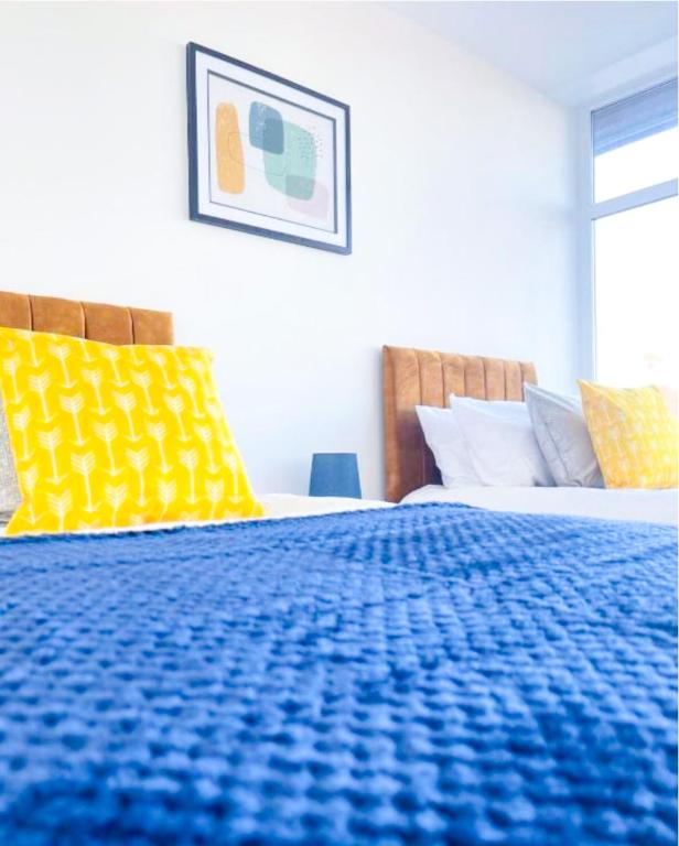 a bedroom with a blue bed with yellow pillows at The Felix Apartments - 1 Bedroom - WIFI - FREE Parking in Flitwick