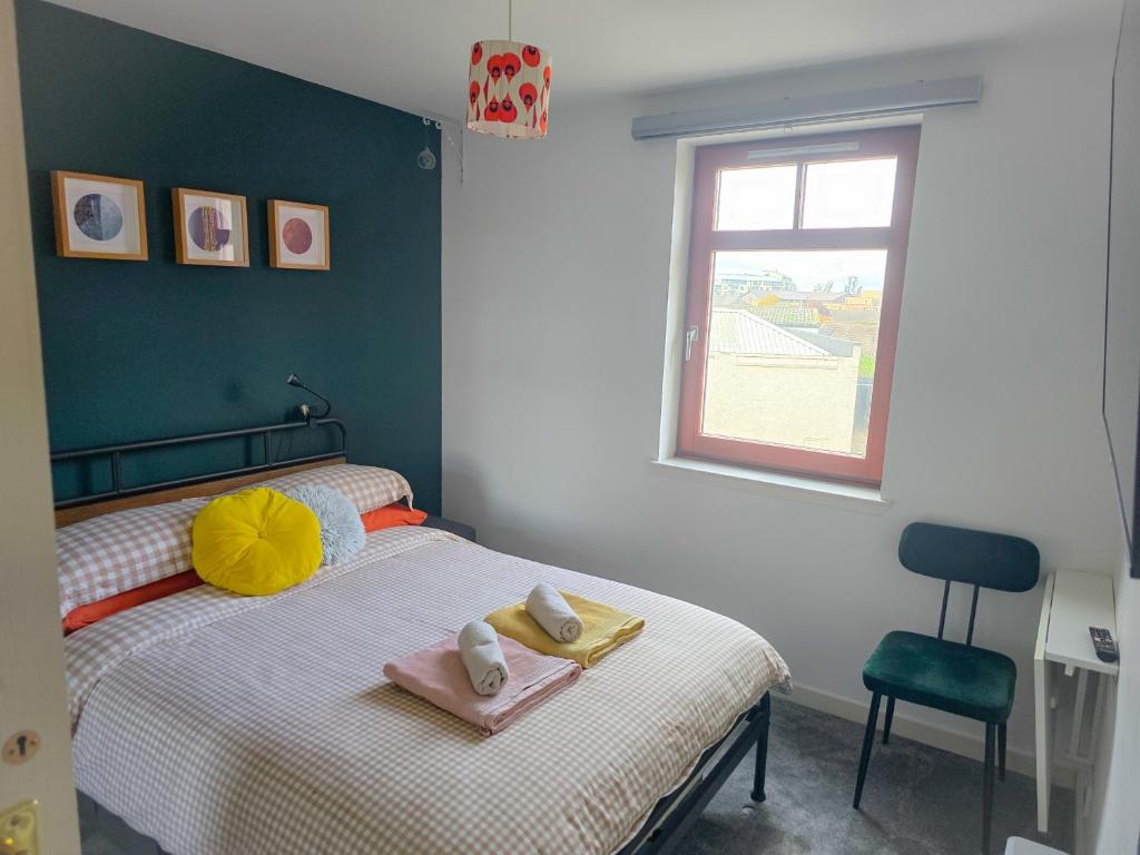 a bedroom with a bed with towels and a window at Leith Double Rooms in Shared Flat Near The Shore and Tram in Edinburgh