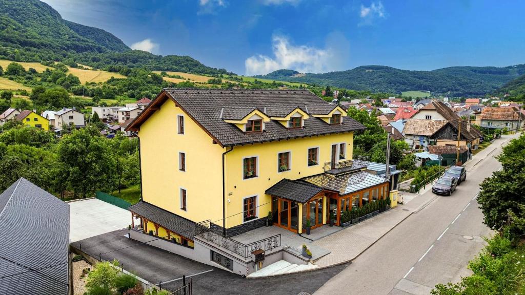 a large yellow house on a street in a town at Penzión Pod Babou in Omšenie